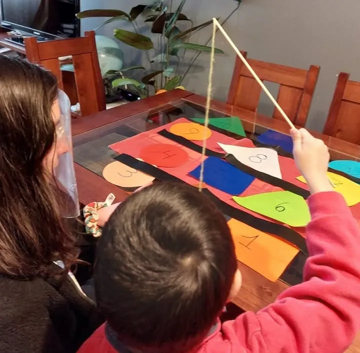 Catalina en una sesión, jugando a pescar números de colores con un niño